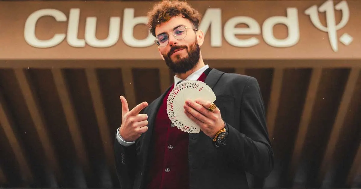 Sebastien Pieta tenant un jeu de carte devant un batiment du clubmed.